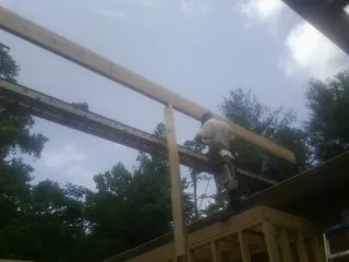 Carpenter setting a ridge beam over a new addition frame — Ice Dam Removal by Roofing Brothers in Grasonville