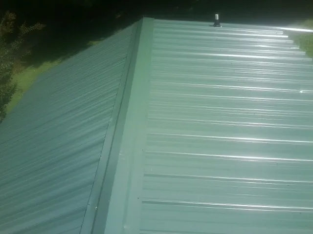 New green metal panels meeting at the ridge of a roof — Flat Roof Repair work by our crew in Grasonville