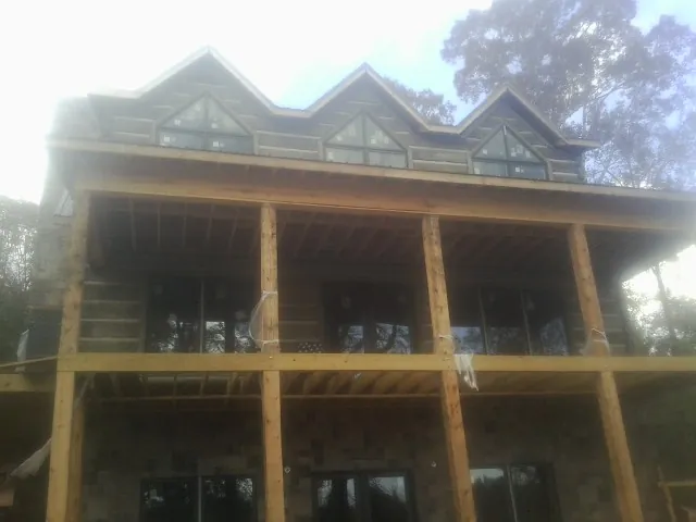 Dormers and porch framing on a large log home under construction — Roof Coating work by our crew in Grasonville