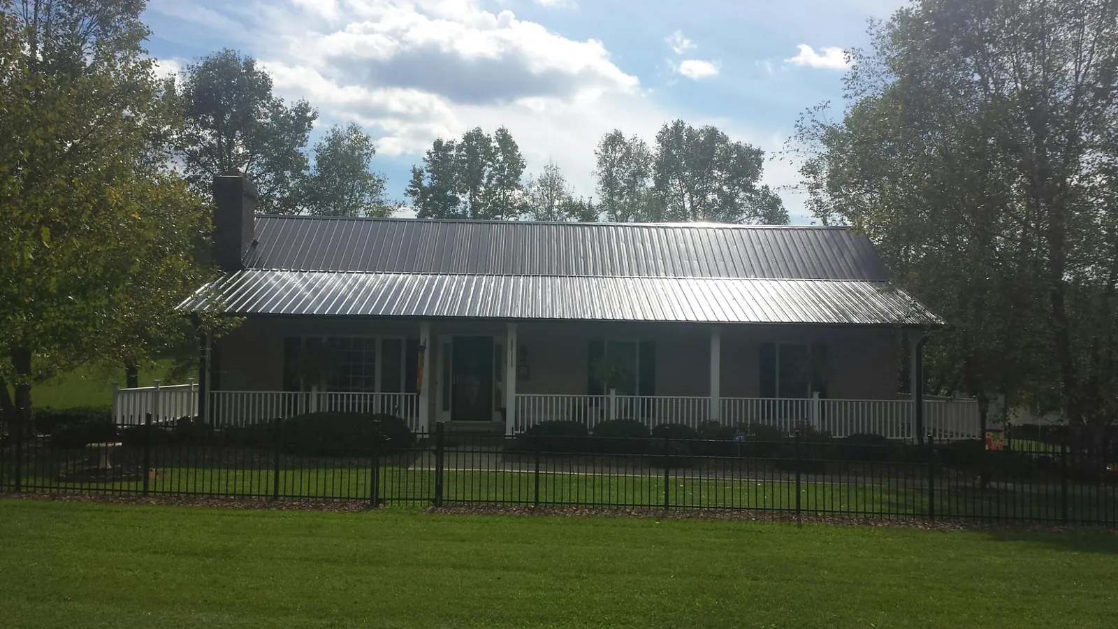 Gray metal roof on a brick ranch with a full width front porch — Gutter Guard Installation work by our crew in Grasonville