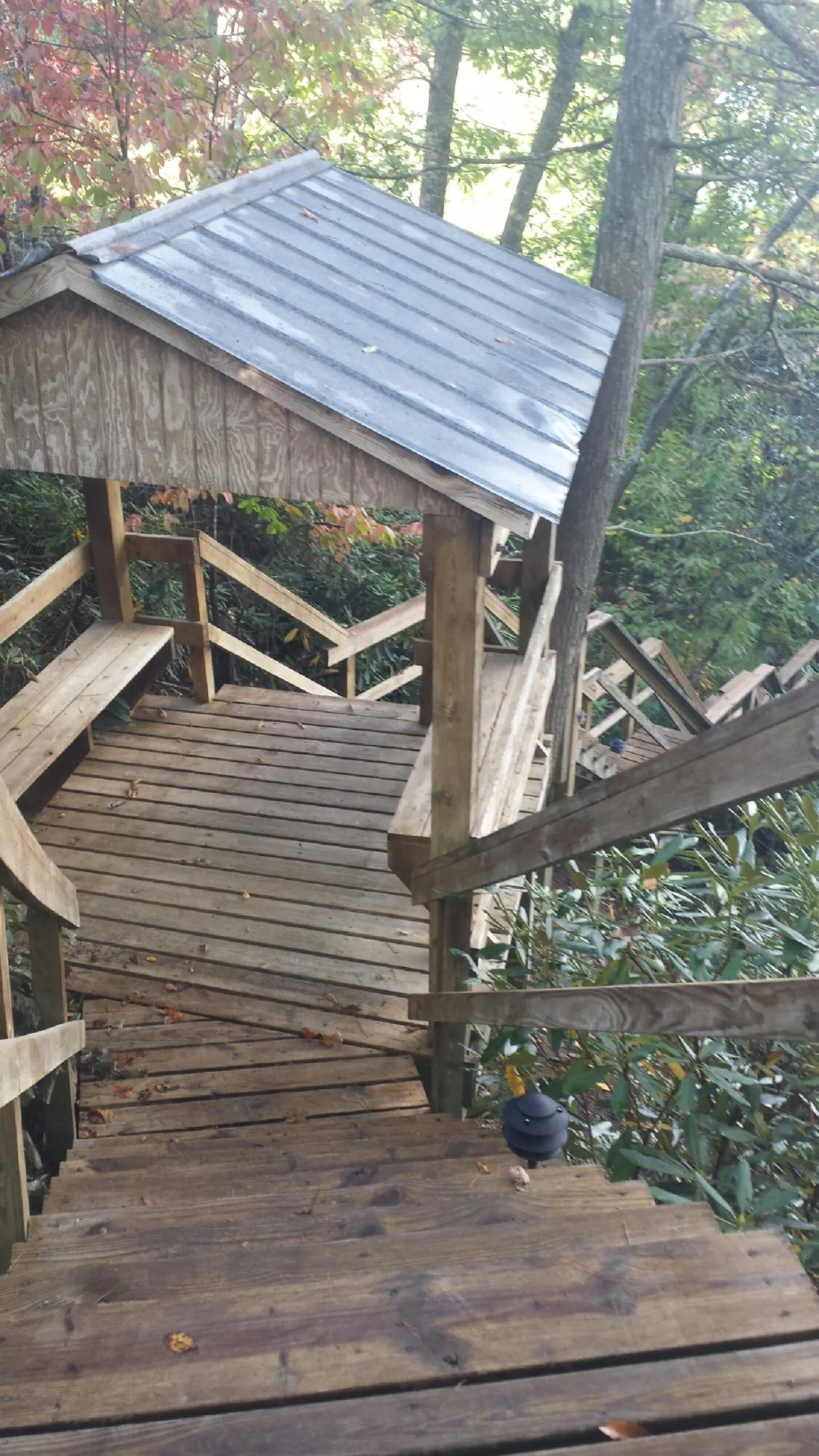 Metal roofed shelter over wooden steps on a wooded walkway — Skylight Repair & Installation work by our crew in Grasonville