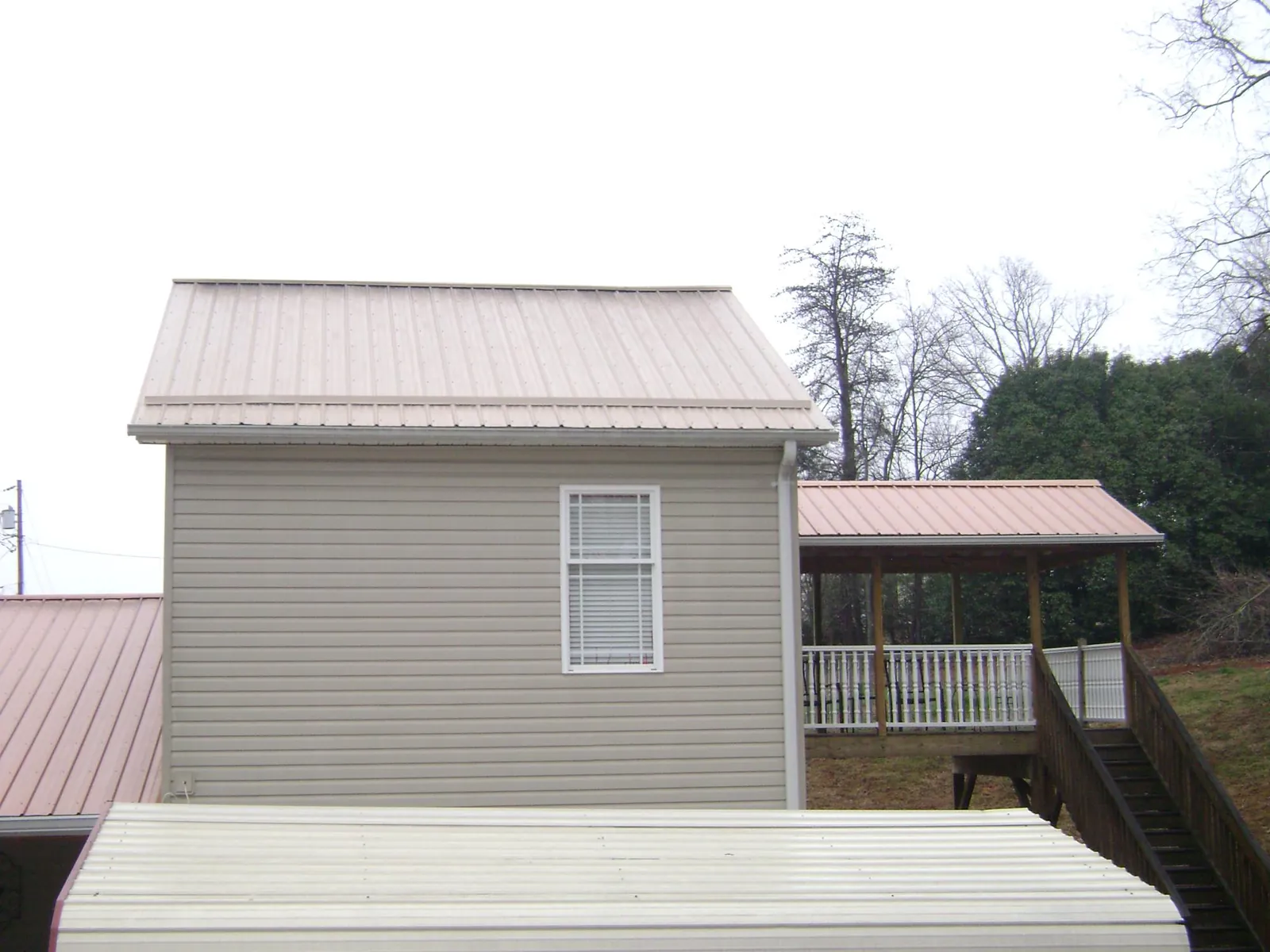 Tan metal roofs on a two story addition and attached porch, from a Roof Replacement job in Grasonville