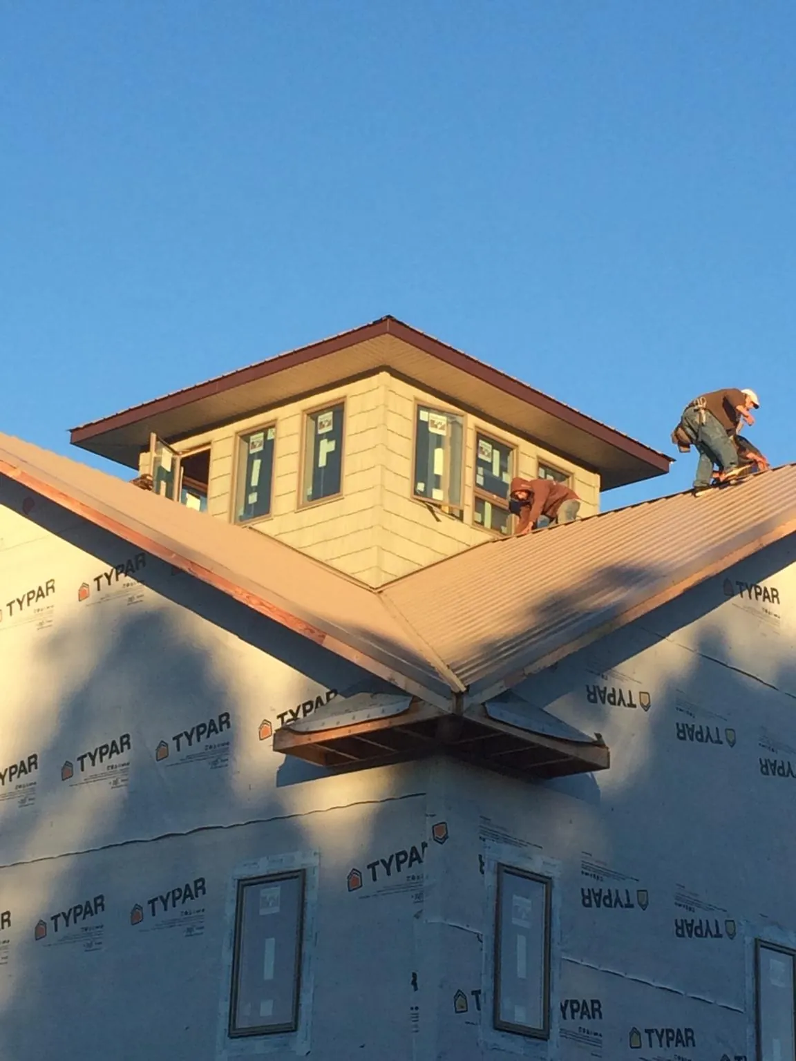 Roofers working around a rooftop cupola on a new metal roof at sunset — Roof Waterproofing in Grasonville by Roofing Brothers